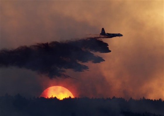 A slurry bomber drops retardant on a burning ridge as the sun sets behind it as a wildfire burns west of Loveland, Colo., on Sept. 12.